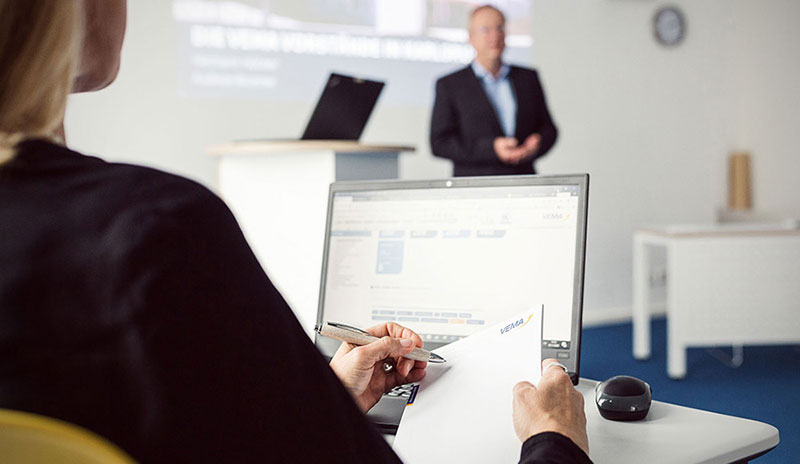 Teilnehmerin macht Notizen am Laptop während einer Business-Präsentation im Seminarraum
